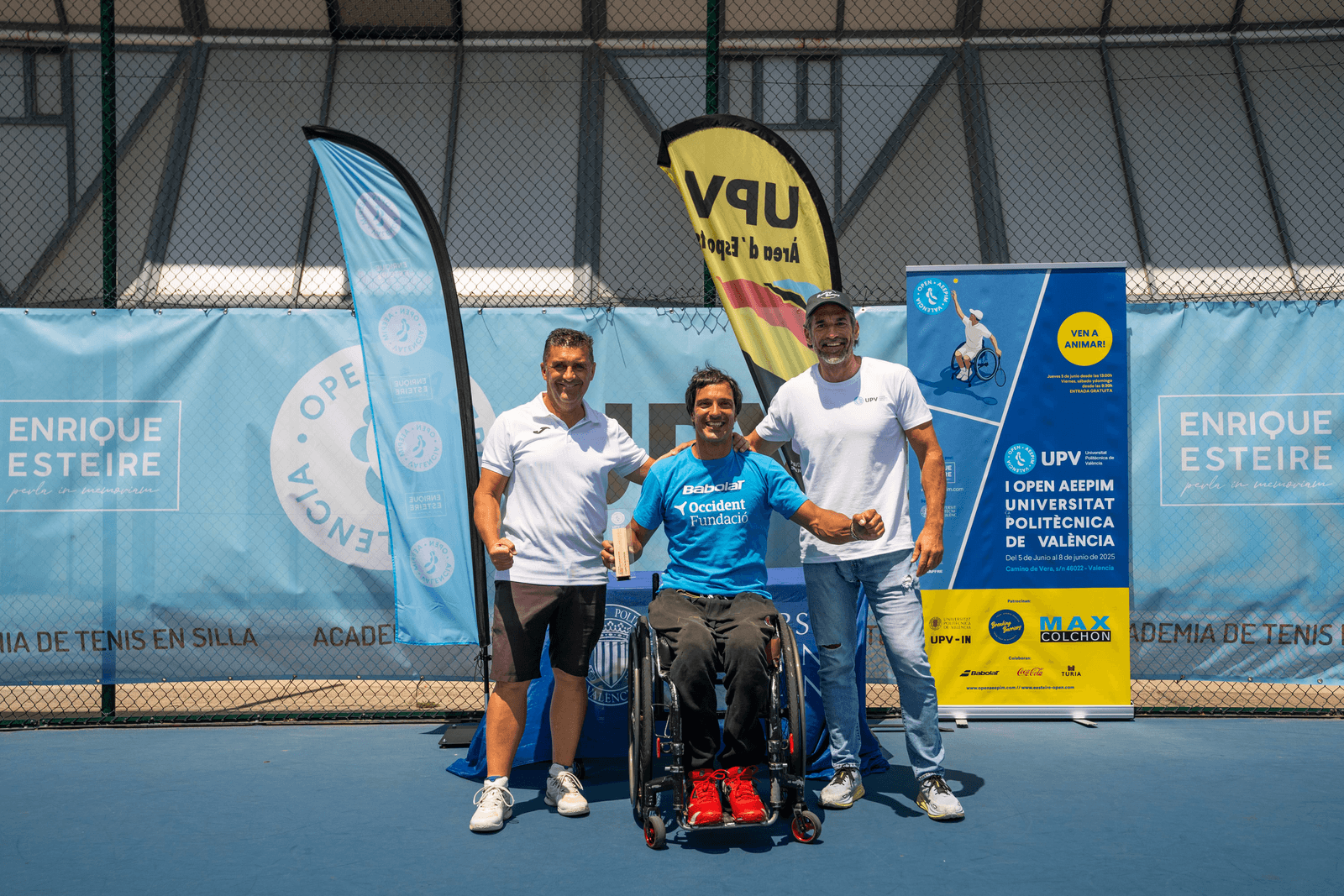 Entrega de premios en pista: jugador en silla con trofeo, equipo y pancartas del Open AEEPIM y UPV